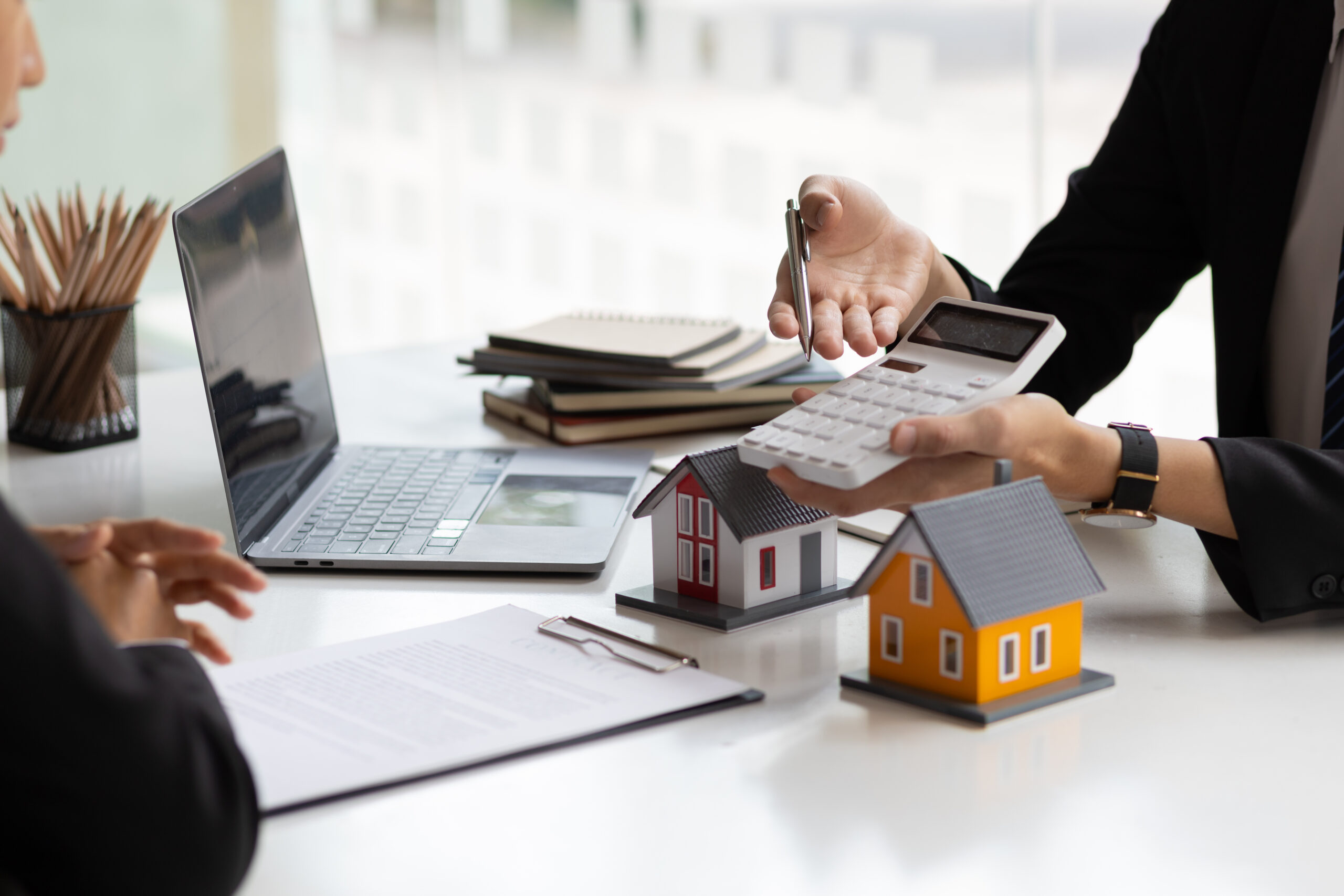 Businessman, real estate agent holding a calculator, presenting a price quote to a client for a house, mortgage, lease, rent, interest, fee, loan, interest.